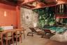 Covered patio featuring exposed timber beams, a natural stone feature wall, a wall-mounted shower fixture, and a built-in swimming pool
