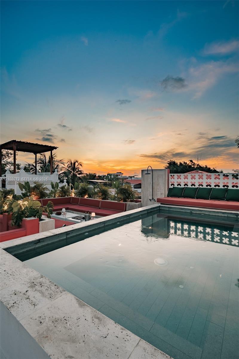 Rooftop terrace featuring a stone-lined pool, built-in masonry seating, a pergola, and decorative open-patterned privacy screening