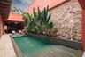 Courtyard pool featuring stone wall masonry, tile surround, integrated landscaping, and recessed wall lighting