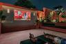 Outdoor courtyard featuring stone flooring, integrated wall-mounted lighting, a built-in stone projection screen, raised stone planters, and perimeter