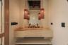 Custom stone floating vanity with an integrated basin, dual wall-mounted faucets, arched wall mirror, and exposed timber ceiling beams