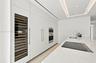 Sleek kitchen featuring custom floor-to-ceiling cabinetry, built-in stainless steel appliances, a glass-front wine refrigerator, and a solid-surface i