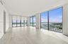 Expansive living area featuring floor-to-ceiling windows, large-format tile flooring, recessed lighting, and a private balcony
