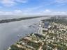 Aerial perspective of a high-rise tower situated on a coastal waterfront featuring direct proximity to a marina and expansive water scenery