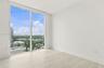 Floor-to-ceiling windows, neutral interior walls, and stone-finish flooring