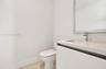 Modern vanity featuring a seamless integrated countertop and sink, wall-mounted mirror with a metallic frame, chrome faucet, and light-toned wood-fini