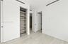 Minimalist interior featuring wood-finish flooring, recessed linear ceiling diffusers, sliding panel doors, and built-in shelving with wood-tone inter
