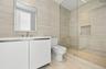Minimalist vanity featuring a smooth-finish white cabinet and rectangular sink with metal fixtures, complemented by wall-to-wall linear-patterned tile