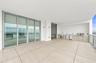 Expansive covered terrace featuring large-format tile flooring, a built-in outdoor kitchen with stainless steel appliances, stone-finish cabinetry, fl