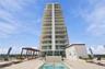 High-rise building exterior featuring tiered balconies with metal railings, elevated terrace level, tiled sundeck, built-in swimming pool, and custom 