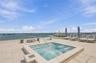 Rooftop terrace featuring stone tile flooring, an integrated jetted spa with a stainless steel handrail, and a frameless glass perimeter railing