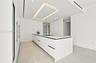 Minimalist kitchen featuring matte white flat-panel cabinetry, a quartz waterfall-edge island, an integrated induction cooktop, recessed lighting, and