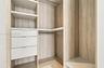 Custom walk-in closet featuring wood-finish cabinetry, open shelving, integrated drawers with metal pulls, and built-in hanging rods