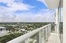 Private balcony featuring large-format tile flooring, glass panel railings, and full-height sliding glass doors