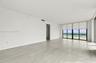 Neutral-toned stone flooring, recessed ceiling lighting, floor-to-ceiling glass sliding doors, and private exterior balcony
