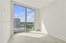 Floor-to-ceiling windows, neutral interior walls, and light-toned tile flooring