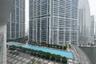 Expansive outdoor terrace featuring multi-level swimming pools, paved stone decking, landscaped trees, and high-rise tower surroundings