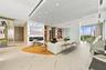 Open-concept interior featuring large-format tile flooring, a floor-to-ceiling stone-clad fireplace wall, custom built-in shelving, a tiered slatted c