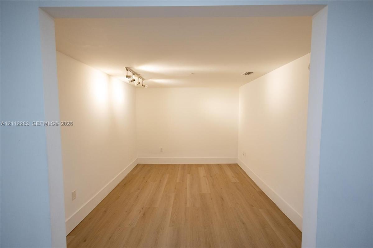 Interior space featuring wood-finish flooring, smooth wall surfaces, and ceiling-mounted track lighting