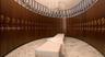 Curved wood cabinetry featuring brass hardware, polished stone flooring, and a multi-tiered crystal chandelier