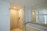 Walk-in shower with frameless glass enclosure, recessed ceiling lighting, wall-mounted handheld showerhead, built-in soaking tub, and square wall-moun