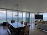 Floor-to-ceiling glass panel windows, polished stone flooring, three-globe pendant lighting, and an expansive balcony