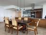 Kitchen featuring stone countertops, integrated wood-toned cabinetry, stainless steel range hood, glass-front upper cabinets, and glass globe pendant 