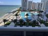 Multi-level outdoor pool area with integrated cabanas, stone-paved sun decks, landscaped palm trees, and oceanfront placement