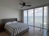 Floor-to-ceiling windows featuring ocean scenery, matte black ceiling fan, and stone flooring