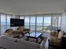 Floor-to-ceiling windows, wrap-around balcony access, stone flooring, and expansive ocean frontage