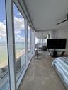 Floor-to-ceiling windows featuring panoramic coastal scenery, large-format tile flooring, and a private balcony with glass railing