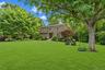Expansive, manicured lawn featuring mature trees and established perimeter landscaping