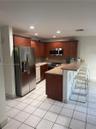 Kitchen featuring cherry-toned wood cabinetry, stainless steel appliances, solid-surface breakfast bar, and tile flooring