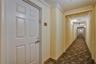 Interior corridor featuring six-panel door with metal hardware, crown molding, and patterned carpeting