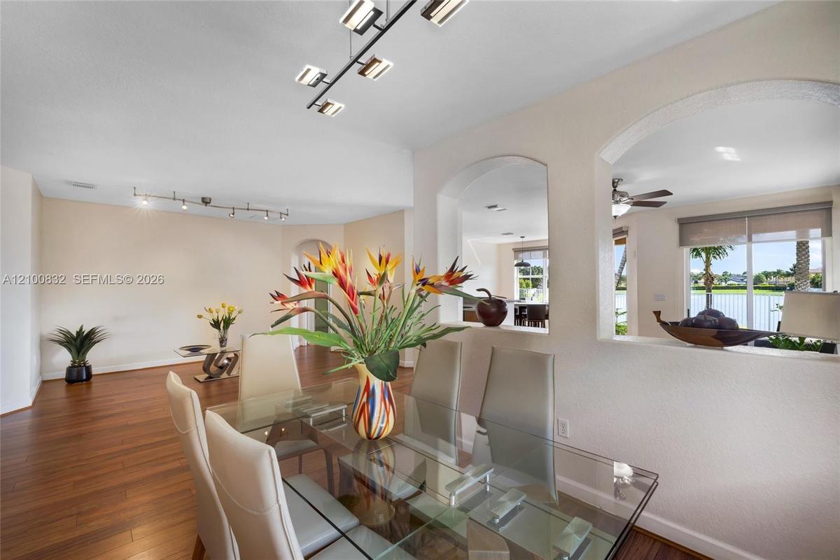 Wood-finish flooring, architectural arched wall cutouts, and contemporary linear track lighting