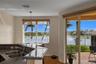 Kitchen featuring a stone-surfaced breakfast bar, double-basin stainless steel sink, wood-finish flooring, and sliding glass doors opening to a brick-