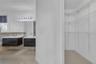 Double floating vanity with integrated rectangular sinks, oversized wall-to-wall mirror, multi-bulb vanity lighting, and walk-in closet featuring whit