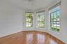 Bay window featuring three arched panes, wood-finish flooring, and a ceiling-mounted fan