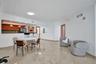 Open-concept area featuring tile flooring, kitchen with wood-finish cabinetry, breakfast bar, and recessed lighting