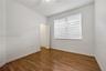 Interior room featuring wood-finish flooring, a ceiling fan, and a window with horizontal blinds