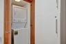 Stacked laundry appliance set within a recessed closet featuring wood-finish door frames and integrated cabinetry with brushed metal hardware