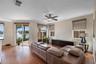 Living area featuring wood-finish flooring, sliding glass doors, built-in dark cabinetry, and a ceiling fan with integrated lighting