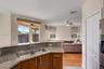 Kitchen featuring a raised breakfast bar with stone-finish countertops, stainless steel dual-basin undermount sink, and wood-finish cabinetry