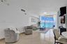 Living space featuring polished stone tile flooring, floor-to-ceiling glass paneling, and access to a private balcony