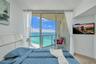 Floor-to-ceiling glass sliding doors opening to an exterior balcony with a glass railing, complemented by expansive ocean scenery