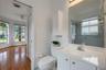 Bathroom featuring a white vanity with an integrated sink, a large wall-mounted mirror, a tub-shower combination with sliding glass doors, and a built