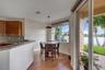 Kitchen featuring wood cabinetry, stone countertops, wood-finish flooring, a pendant light fixture, and sliding glass doors to a paved patio