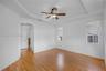 Tray ceiling with a central multi-blade ceiling fan, wood-finish flooring, and arched entryway