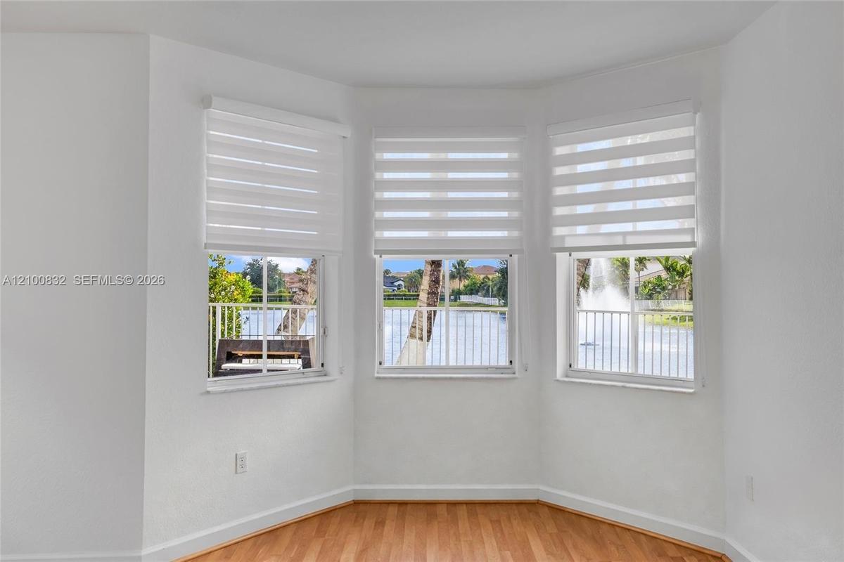 Bay window featuring wood-finish flooring, multi-pane windows, and light-filtering roller shades