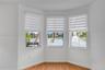 Bay window featuring wood-finish flooring, multi-pane windows, and light-filtering roller shades